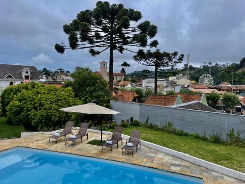 uma piscina com duas cadeiras e um guarda-sol em Casa Três Rios - Campos do Jordão em Campos do Jordão