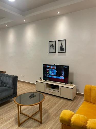 sala de estar con TV, sofá y mesa en Villa akassato en Golo-Tokpa
