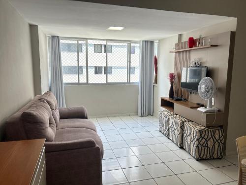 uma sala de estar com um sofá e uma TV em lindo apartamento de frente para à praia de pajuçara em Maceió