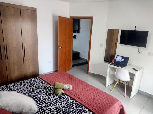 a bedroom with a bed and a desk with a laptop at Flat Ideal para conexão 5 in Guarulhos