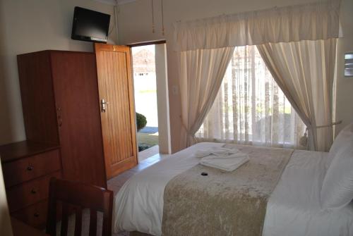 Un dormitorio con una cama y una ventana grande. en LeHiel Guesthouse, en Lichtenburg