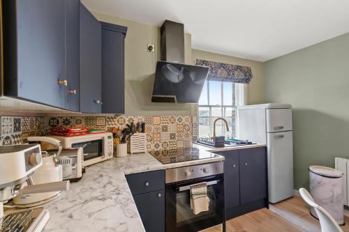a kitchen with blue cabinets and a stove top oven at BridgeCity Modern 2 Bed flat Ashford Town Centre Pet Friendly in Kent