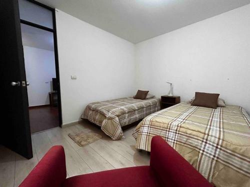 ハラパにあるRinconcito de Paz en Xalapaのベッド2台と赤いソファが備わる客室です。