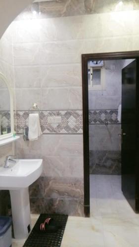 ein Bad mit einem Waschbecken, einem Spiegel und einer Dusche in der Unterkunft شقق روز شروره للشقق المخدومة in Sharorah