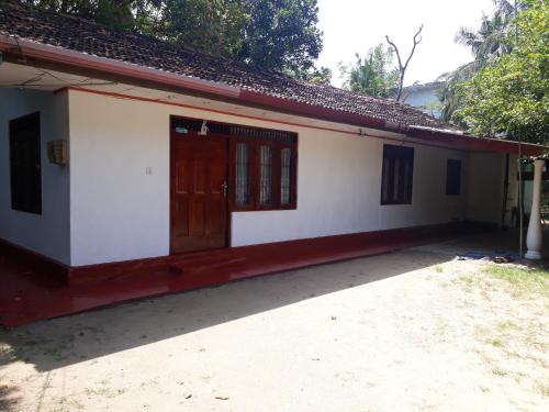 a small white house with a red door at G7 Villa in Weligama