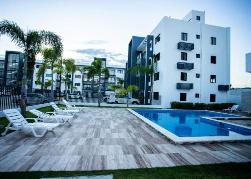 a swimming pool with lounge chairs and a building at Tu penthouse en torre real Vl monumental in Santiago de los Caballeros