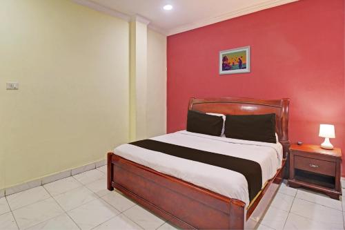 Hotel Ruma Near Nampally Railway Station في حيدر أباد: غرفة نوم بسرير وجدار احمر