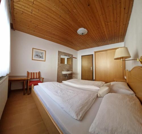 a bedroom with two beds and a wooden ceiling at Almhof Grub in Wagrain