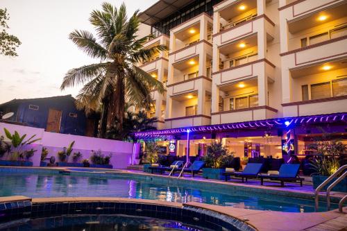 a hotel with a swimming pool in front of a building at La Oasis by Meraden ,Goa in Anjuna