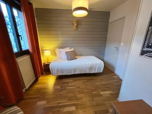 a bedroom with a white bed and a wooden floor at Hôtel La Rencluse in Luchon