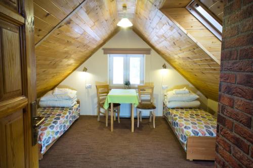 a room with two beds and a table in a attic at Dobra Miejscówka in Krynica Zdrój