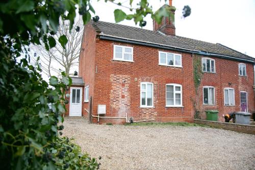 uma casa de tijolos com um grande quintal em frente em Colney Lane Lodge em Colney