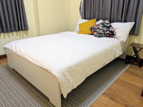 a bed with white sheets and pillows in a bedroom at Entire 2-storey house, 2 br, 2 toilet and shower, 2 car parks, only 400 m from MRT Huai Kwang in Ban Na Song