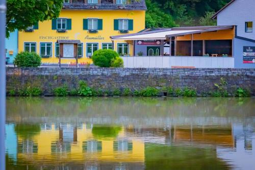 a yellow building next to a body of water at Fischgasthof Aumüller in Obermühl