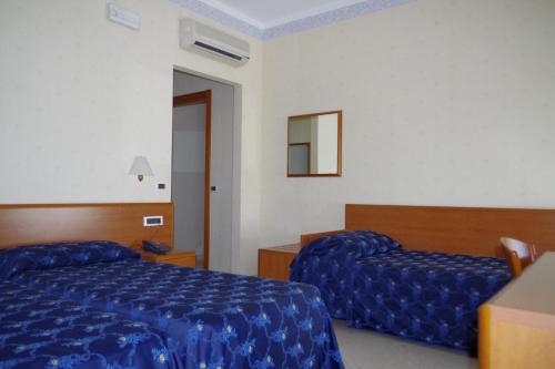 a hotel room with two beds and a mirror at Hotel Kroma in Ragusa