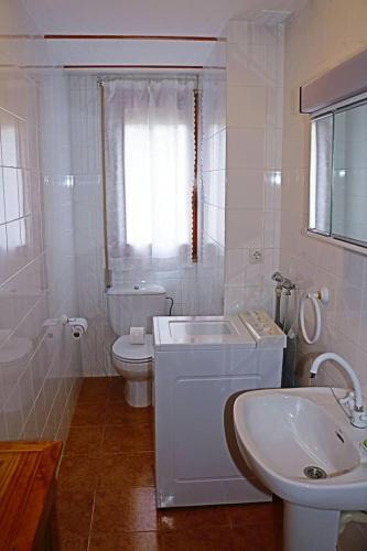 a white bathroom with a sink and a tub and a toilet at L'arome de Ainsa in Aínsa