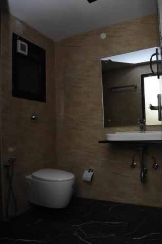 a bathroom with a toilet and a sink and a mirror at SANANDREAS HOTEL Yogiroomsonline in Kodaikānāl
