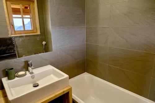 a bathroom with a sink and a bath tub at Parnasse - Appt 5 étoiles dans Chalet Moderne, vue exceptionnelle terrasse et cheminée in Villard-Reculas