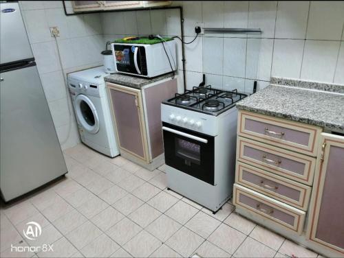 a kitchen with a stove and a microwave at Boys room with sharing washrooms in Sharjah