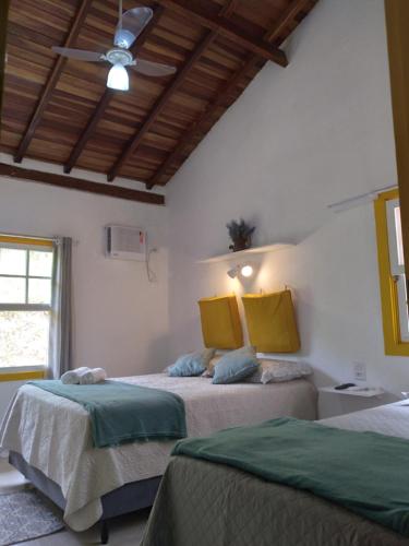 um quarto com 2 camas e uma ventoinha de tecto em Fazenda do Bosque - Pousada e Capril em Paraty