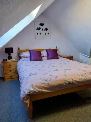 1 dormitorio con 1 cama con almohadas moradas en Gite Albert, en Scrignac