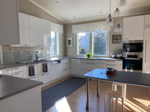 a large kitchen with white cabinets and a blue table at Pajupilli 1-10 henkilölle in Kajaani