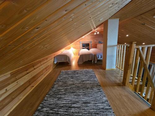 a attic room with two beds and a rug at Tahko Villa Vaarna in Tahkovuori