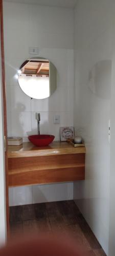 La salle de bains est pourvue d'un lavabo rouge et d'un miroir. dans l'établissement Estrela da Montanha 2, à Santo Antônio do Pinhal