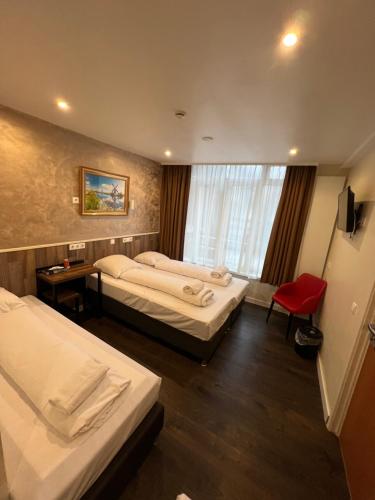 a hotel room with two beds and a red chair at Dam Hotel in Amsterdam