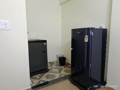 a black refrigerator in a room with a tile floor at Sri Vidya Palace in Udupi
