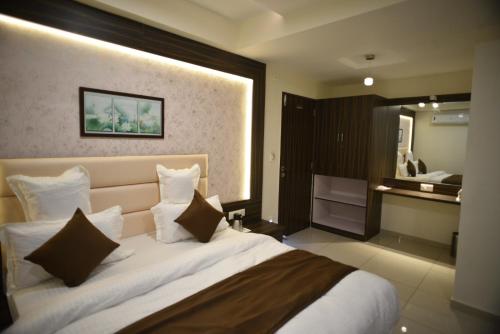 a bedroom with a large white bed with pillows at Hotel Royal Residency in Vadodara