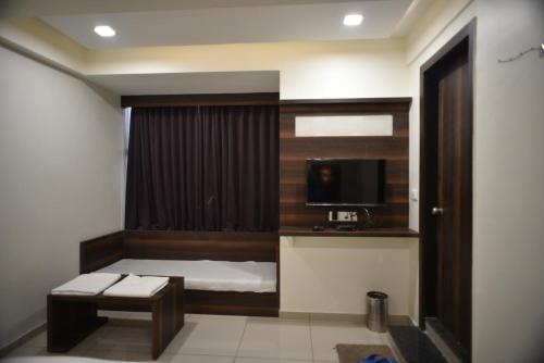 a small room with a bed and a television at Hotel Royal Residency in Vadodara