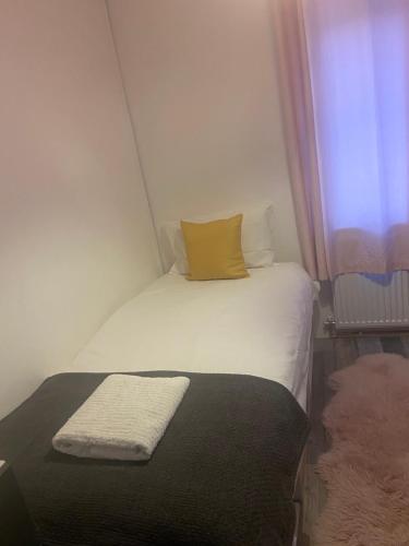 een kleine slaapkamer met een wit bed en een geel kussen bij 11 Lygon Walk 