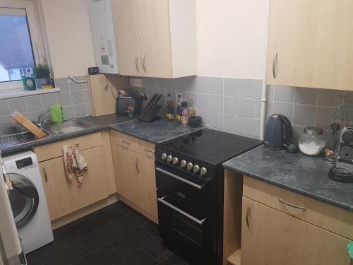 a kitchen with a black stove and a sink at Stylish Double Room in shared apartment in Oxfordshire in Oxford