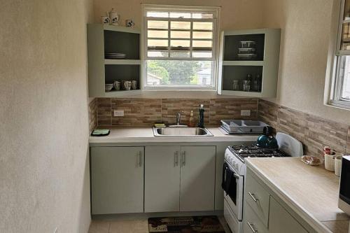 una cocina con armarios blancos y fregadero en Seclusion Studio Apartment., en Saint Phillip