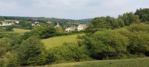 a house on top of a green hill with trees at Highfield House, Parracombe, Modern B&B in Parracombe