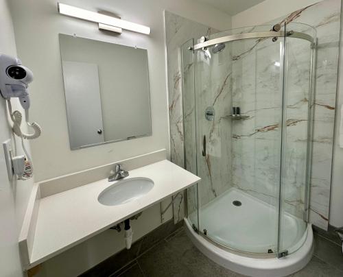 uma casa de banho com um lavatório e uma cabina de duche em vidro. em Royal Inn and Suites Charlotte Airport em Charlotte