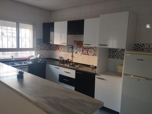 a kitchen with white cabinets and a white refrigerator at Appartement Jad in Tunis