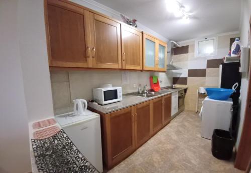 una pequeña cocina con armarios de madera y microondas en AL - Perola Dourada, en Santana