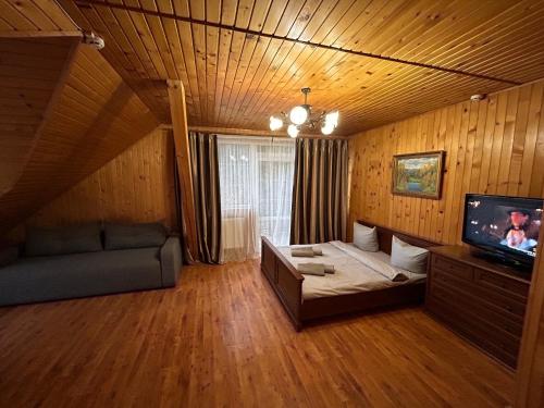 een woonkamer met een bank en een flatscreen-tv bij Любе in Yablunytsia