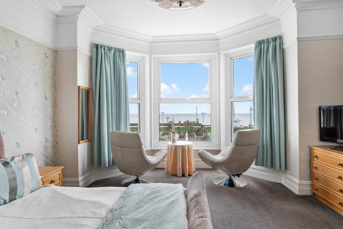 een slaapkamer met een bed en 2 stoelen en een tafel bij Marine Hotel in Paignton
