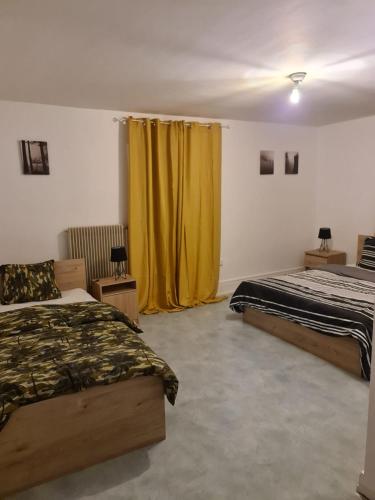 - une chambre avec 2 lits et un rideau jaune dans l'établissement Grand appartement de 3 chambres moderne et spacieux, entièrement meublé, à Belfort