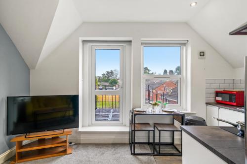a kitchen with a flat screen tv and two windows at BridgeCity The Sleek Modern Condo - Maidstone Gem - f9 in Kent