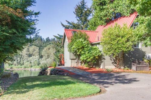 a house with a red roof next to a lake at Milwaukie Riverfront Guest House in Milwaukie