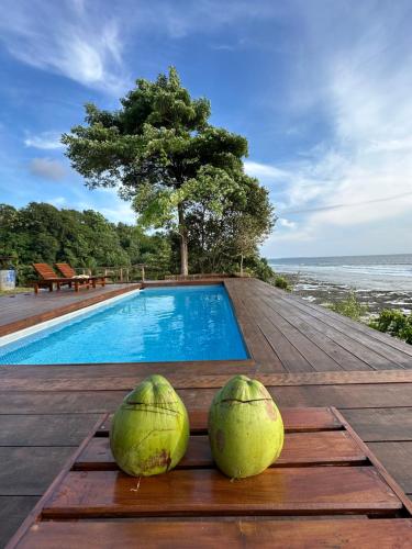 two coconuts sitting on a wooden table next to a swimming pool at BatuRundung Surf Resort in Naibos