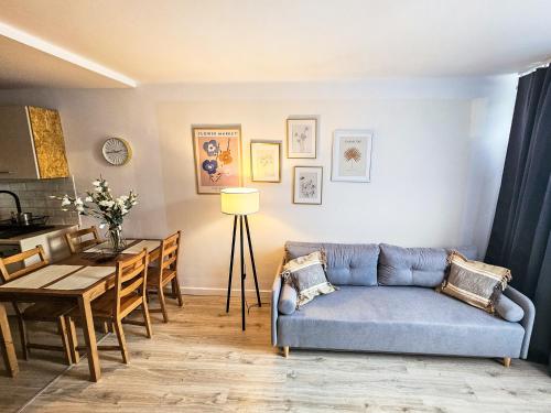 a living room with a blue couch and a table at White Apartment Grzybowska in Warsaw