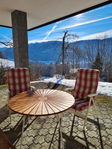 2 sillas y una mesa con sombrilla en el patio en Ferienhaus Buchen en Schwarzenberg im Bregenzerwald