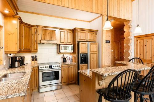 a kitchen with wooden cabinets and a stove top oven at Chalet White Rabbit au Lac Fiddler in Mille-Isles