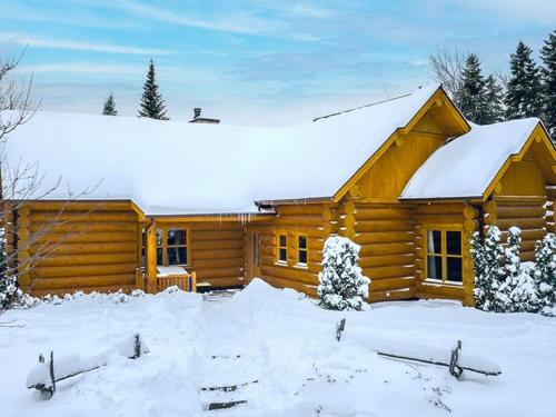 a log cabin in the snow with snow at Chalet White Rabbit au Lac Fiddler in Mille-Isles