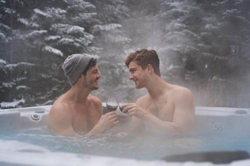 two men sitting in a bathtub withcold water at Chalet White Rabbit au Lac Fiddler in Mille-Isles